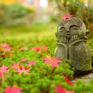 Feuille d'érable sur une petite sculpture de moine dans un jardin japonais