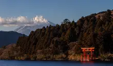 Torii gate on a lake edge with Mt Fuji in the background.