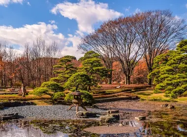 Pond with stone lantern on the edge and trees in the background