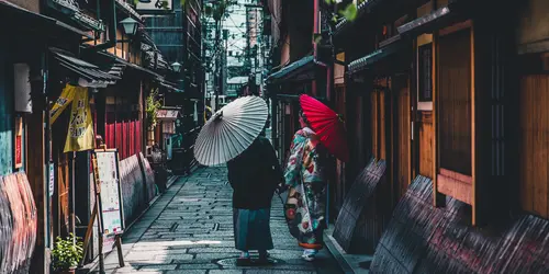 Couple walking on street while holding umbrella in Kyoto