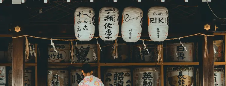woman wearing orange and white kimono dress standing near an Old Shop